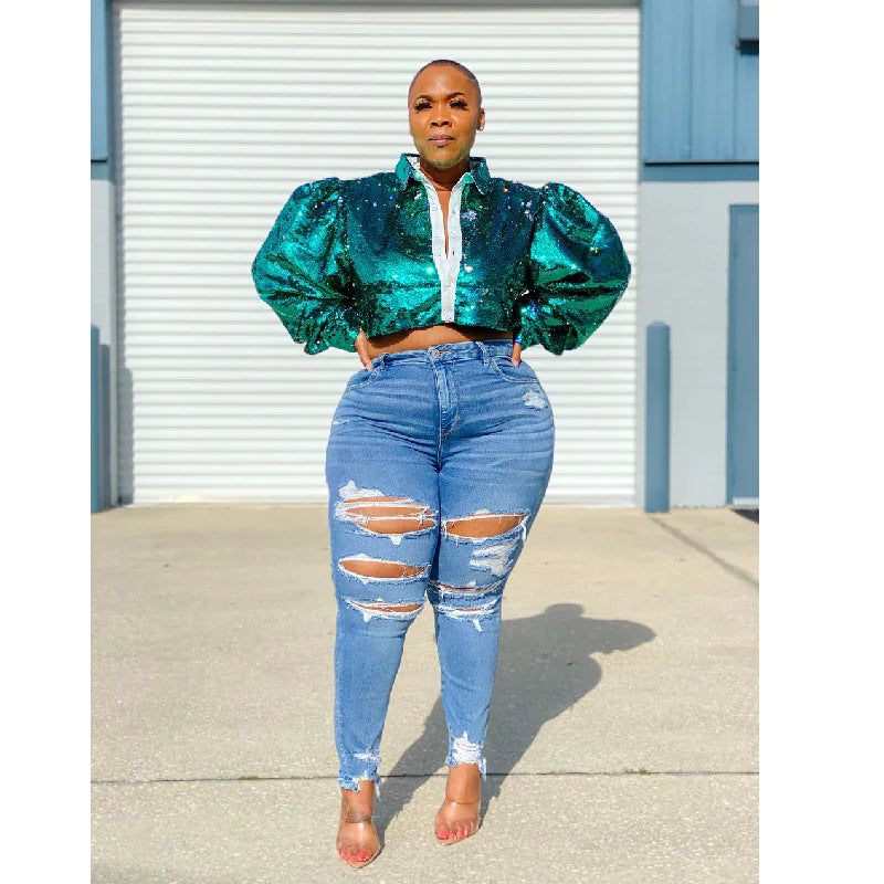 A woman wearing a green sequined top and large denim trousers for women, showcasing a trendy distressed style.