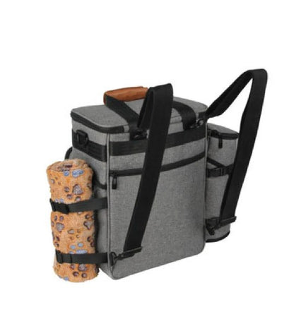 A golden retriever sitting next to a Pet Essentials Travel Organizer filled with pet supplies and travel bowls.