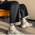 Chic High-Waist Cargo Denim featuring rolled cuffs and paired with trendy sneakers, seated in a stylish environment.
