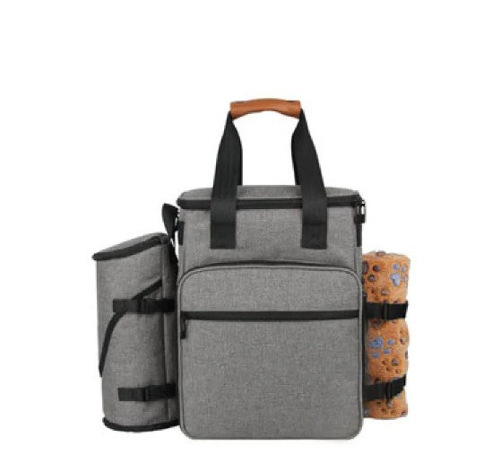 A golden retriever sitting next to a Pet Essentials Travel Organizer filled with pet supplies and travel bowls.
